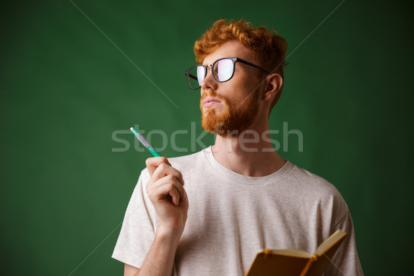 Close-up view of thinking bearded young man in white tshirt hold Stock photo © deandrobot