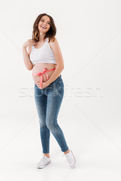 Cheerful pregnant woman standing isolated with bow on belly Stock photo © deandrobot