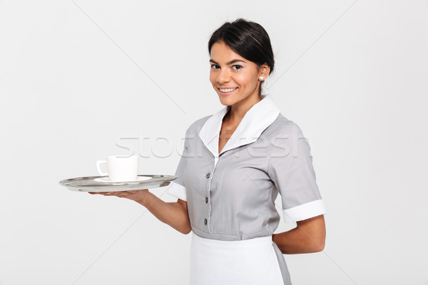 Portrait of young cheerful woman in gray uniform holding metal t Stock photo © deandrobot