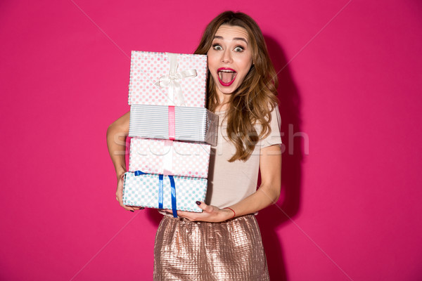 Shocked young woman holding surprise gifts boxes. Stock photo © deandrobot