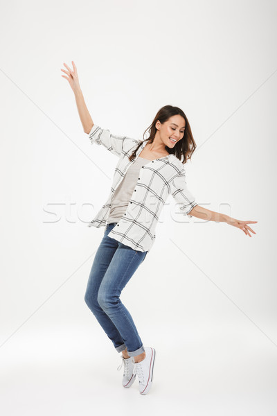 Full length image of Cheerful brunette woman in shirt dancing Stock photo © deandrobot