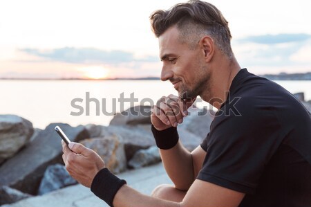 Portrait of a strong sportsman using mobile phone Stock photo © deandrobot