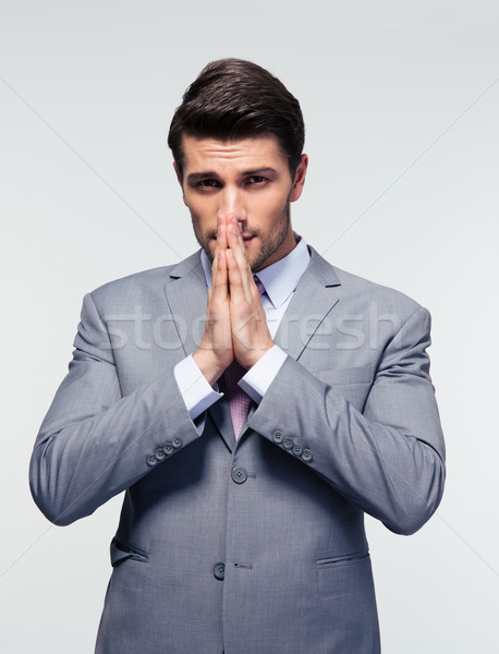 Businessman praying over gray background Stock photo © deandrobot