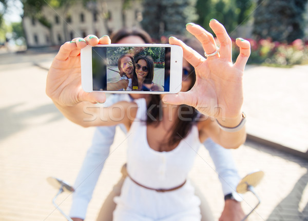 Happy couple showing smartphone screen while making selfie  outdoors Stock photo © deandrobot