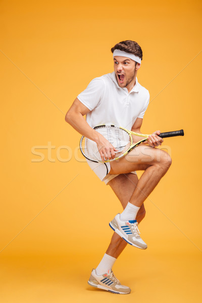 Comical young man tennis player with racket shouting and joking Stock photo © deandrobot