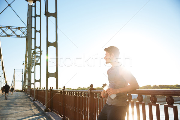 Sports man resting after running while leaning against bridge railing Stock photo © deandrobot