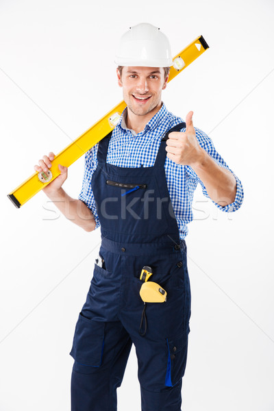 Smiling male builder standing and showing thumbs up gesture Stock photo © deandrobot