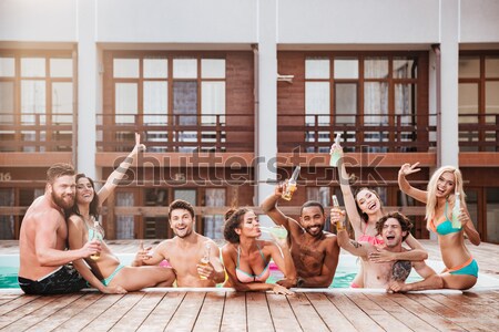 Croup of cheerful happy friends drinking beer at the pool Stock photo © deandrobot