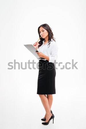 Beautiful pensive asian businesswoman holding clipboard and thinking about something Stock photo © deandrobot