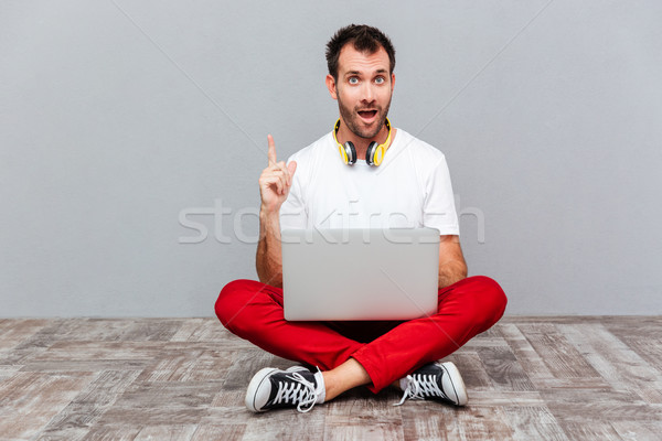 человека сидят полу ноутбука указывая пальца Сток-фото © deandrobot
