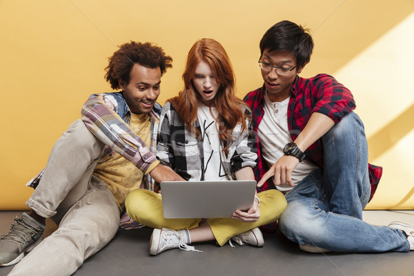 Three amazed people pointing on the screen of laptop together Stock photo © deandrobot