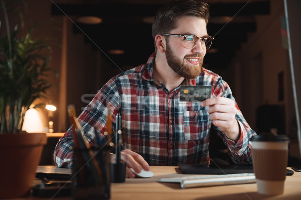 Stock photo: Young smiling businessman with computer and credit card shopping online