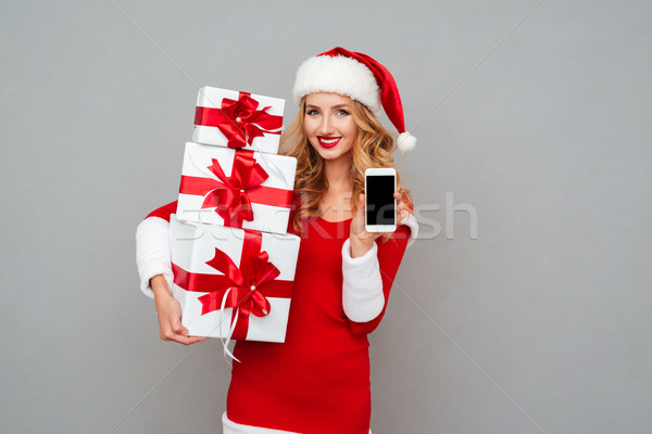 Woman in red santa claus outfit holding blank screen phone Stock photo © deandrobot