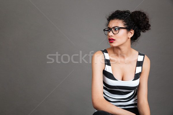 Serious frowning african woman in glasses sitting and looking away Stock photo © deandrobot