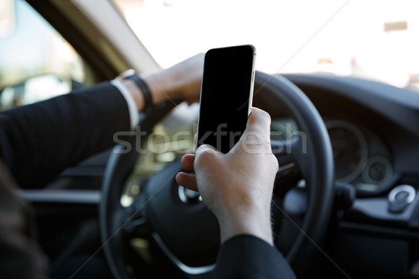 Férfi öltöny vezetés autó tart mobiltelefon Stock fotó © deandrobot