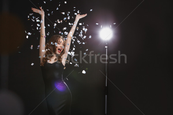 Alegre mulher jovem as mãos levantadas dança elegante Foto stock © deandrobot