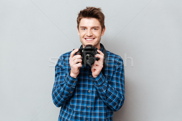 Young man holding his camera in hands isolated Stock photo © deandrobot