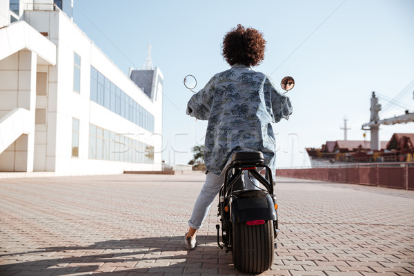 Stock photo: Full-length back view image of curly girl rides on motorbike