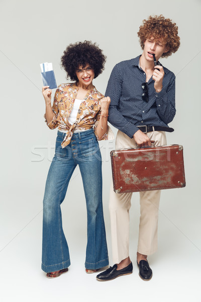 Emotional happy retro loving couple holding suitcase passport and tickets. Stock photo © deandrobot