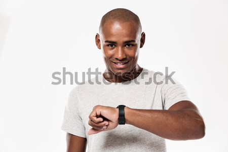 Happy young african man using watch. Stock photo © deandrobot