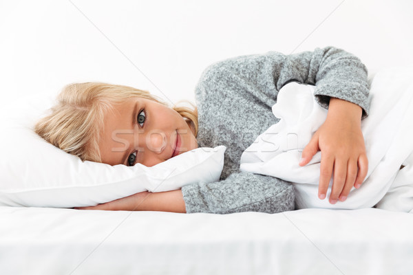 Close-up portrait of beautiful little kid lying on bed with hand Stock photo © deandrobot