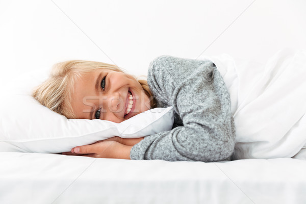 Close-up portrait of laughing little girl lying on bed with hand Stock photo © deandrobot