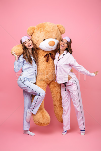 Cheerful friends women in pajamas hug big teddy toy bear Stock photo © deandrobot