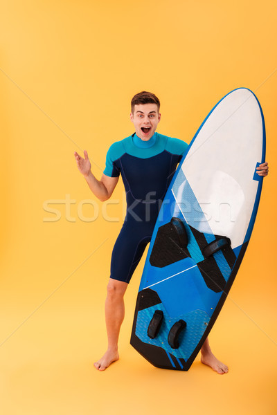 Full length photo of happy exited brunette man in swimsuit holdi Stock photo © deandrobot