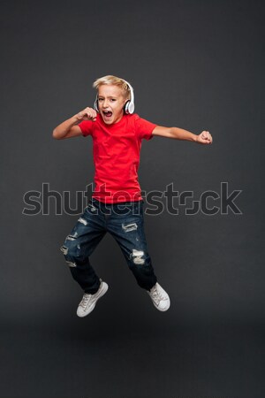 Emotional little boy child listening music with headphones dancing. Stock photo © deandrobot