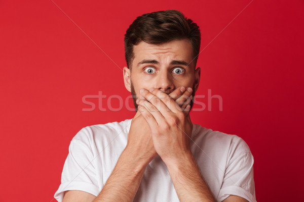 Scared young man covering mouth with hands Stock photo © deandrobot