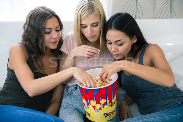 Three girlfriends eating popcorn Stock photo © deandrobot