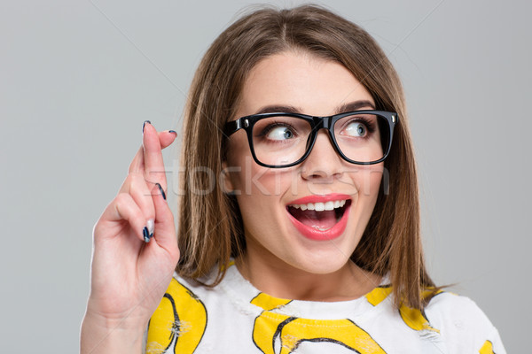 Cheerful woman with crossed fingers looking away  Stock photo © deandrobot