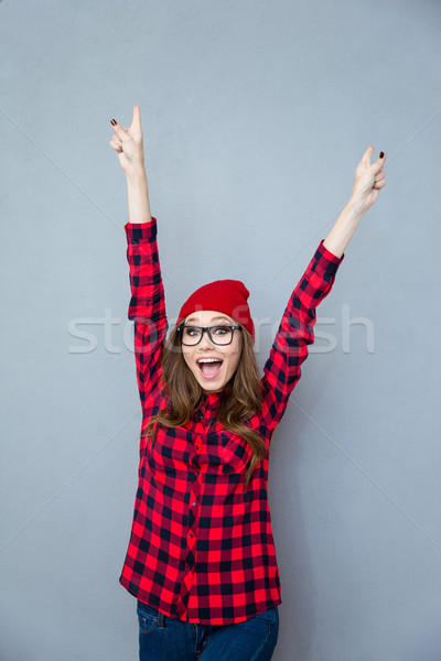 Cheerful woman standing with raised hands up Stock photo © deandrobot