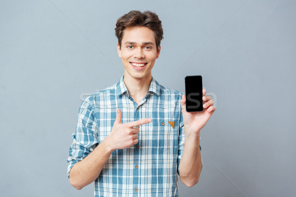 Smiling man showing blank smartphone screen Stock photo © deandrobot