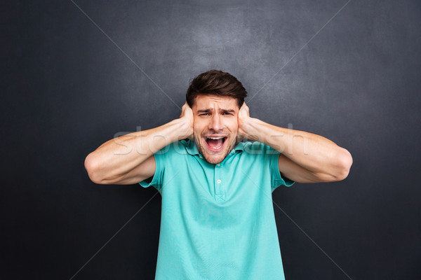 Casual man covering his ears and shouting over black background Stock photo © deandrobot