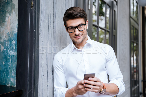 Man using earphones and listening to music from cell phone Stock photo © deandrobot