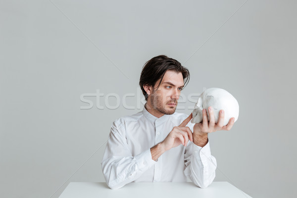 Człowiek posiedzenia wskazując palec podróbka czaszki Zdjęcia stock © deandrobot