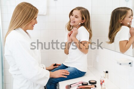 Two happy cheerful women wearing shirts and sitting on bed Stock photo © deandrobot