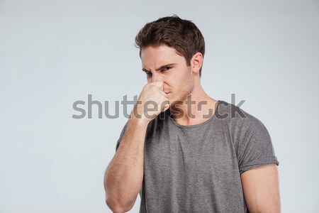 Portrait of a casual man covering his nose with hand Stock photo © deandrobot