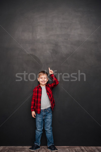 Happy boy standing over chalkboard and pointing up Stock photo © deandrobot