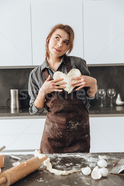 Stock photo: Young incredible lady holding the dough heart