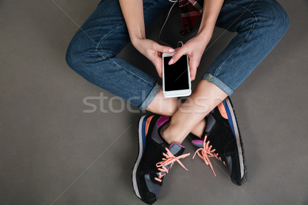 Women crossed legs and hands holding blank screen mobile phone Stock photo © deandrobot