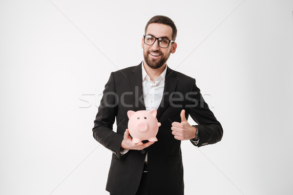 Businessman showing thumbs up gesture and holding moneybox. Stock photo © deandrobot