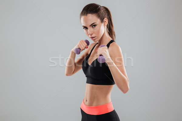 Serious sports woman with dumbbells looking at the camera Stock photo © deandrobot