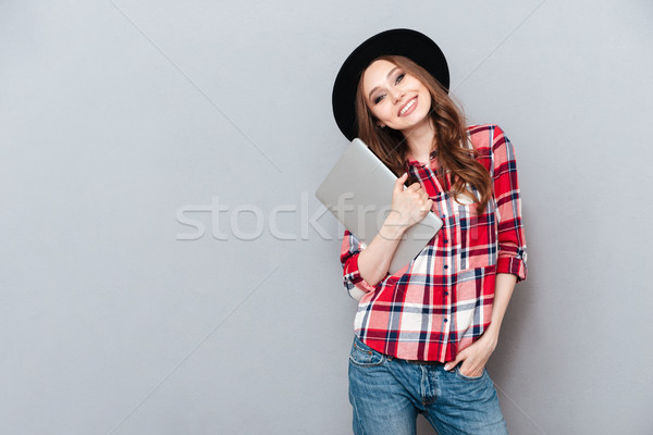 Smiling woman in plaid shirt holding laptop Stock photo © deandrobot