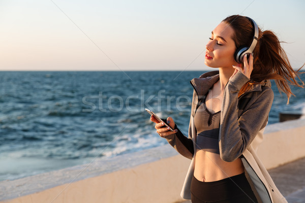 Close-up portrait of cheerful young sport woman listening to mus Stock photo © deandrobot