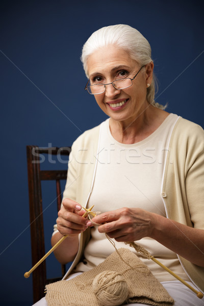 Stock photo: Cheerful old woman knitting. Looking camera.