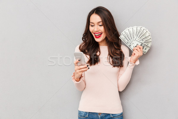 Portrait of attractive brunette female 30s winning lots of money Stock photo © deandrobot