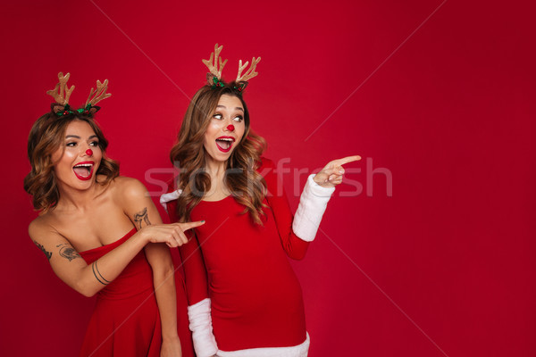 Surprised young women friends wearing christmas deer costumes Stock photo © deandrobot