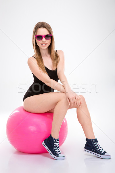 Happy smiling pretty young woman in sunglasses sitting on fitball Stock photo © deandrobot